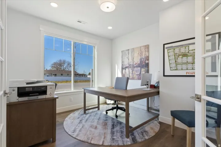 Dedicated office space featuring French doors, wood-finish flooring, a large window, recessed lighting, and a contemporary light fixture