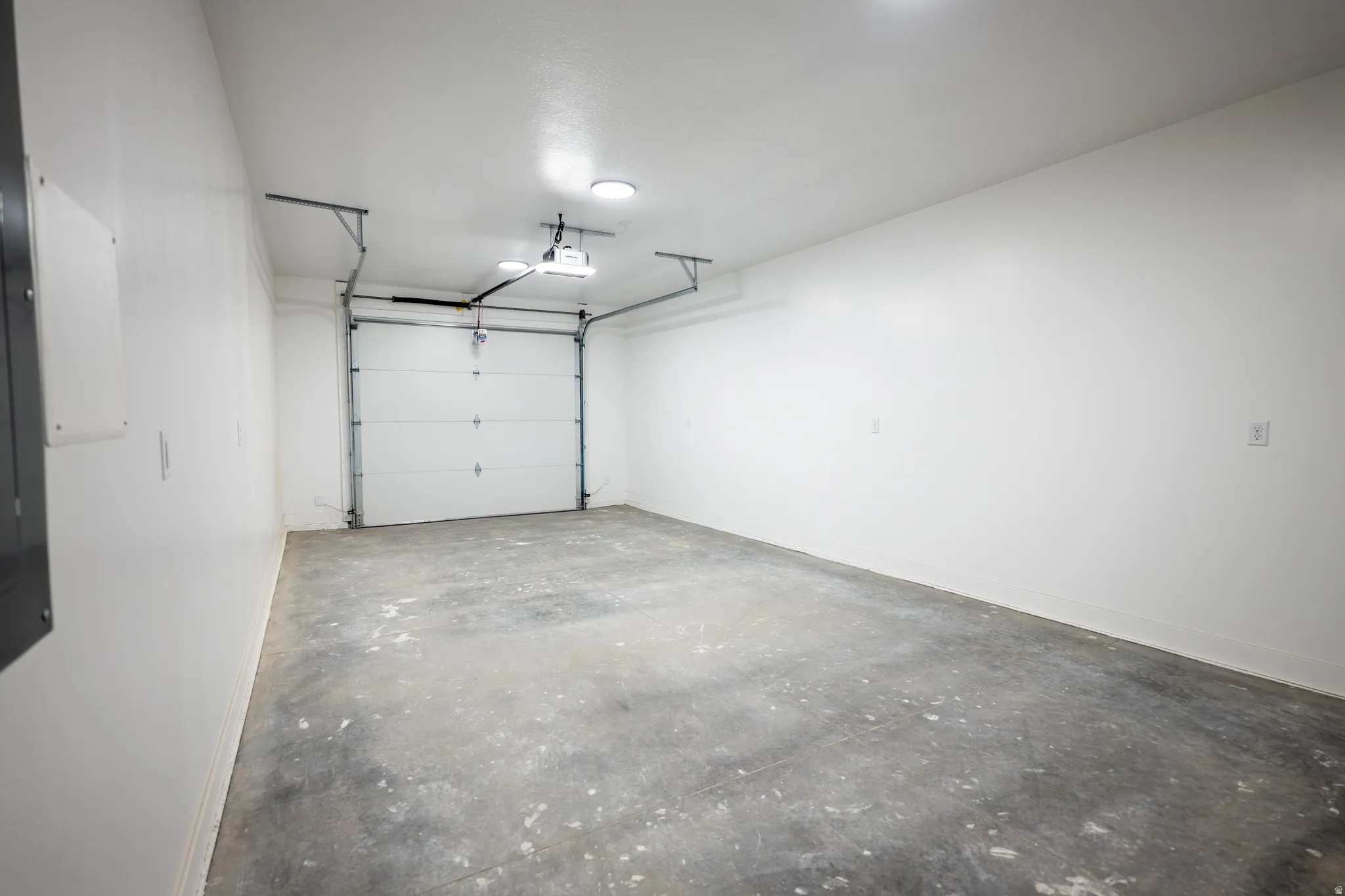 Spacious garage featuring a concrete floor, white painted walls, and a panel garage door