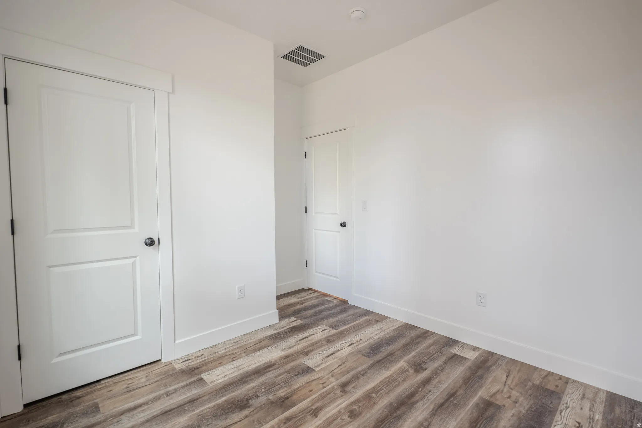 Interior room featuring wood-finish flooring, crisp white walls, and white trim