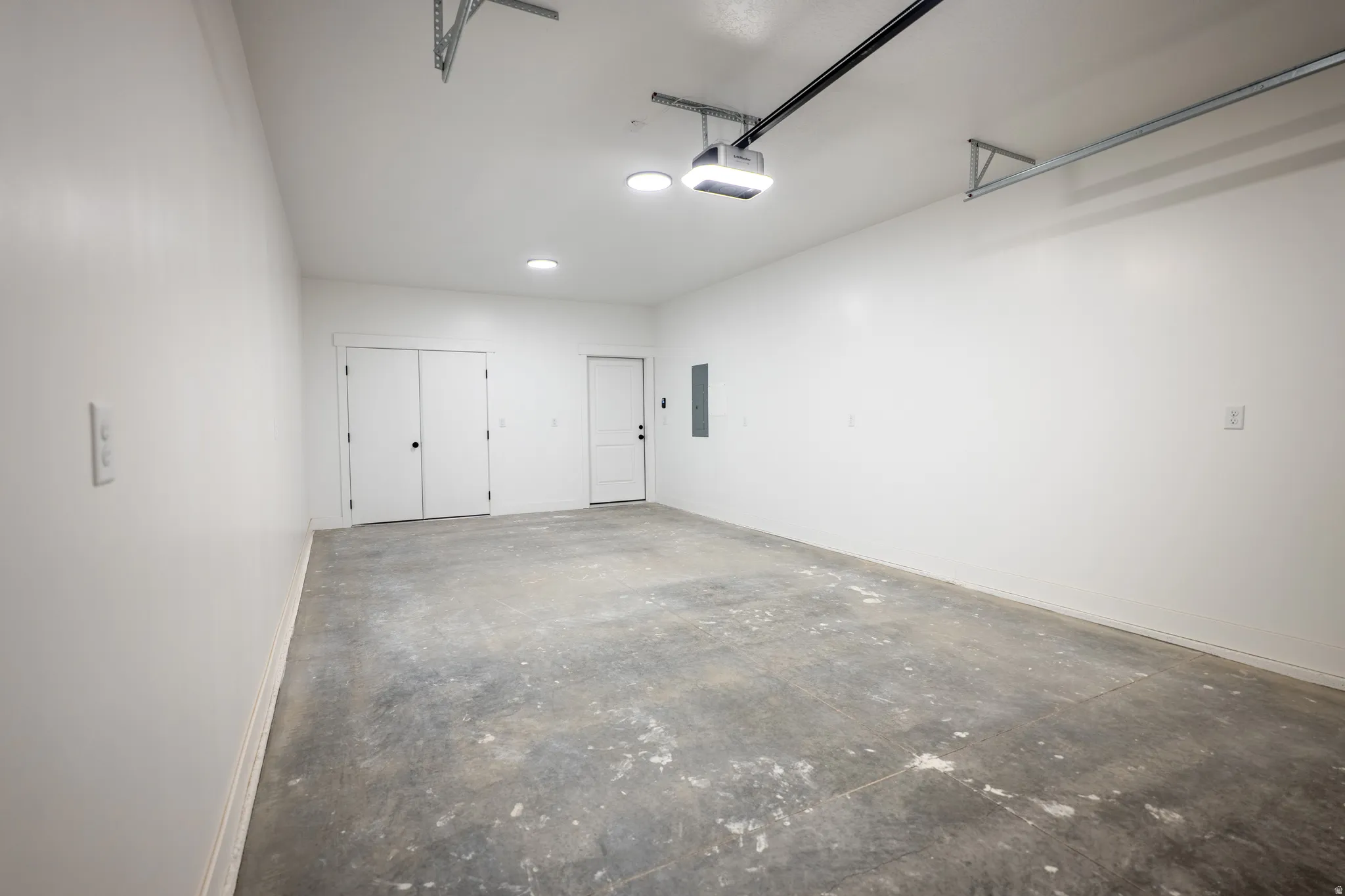 Spacious garage featuring a concrete floor, bright white walls, and recessed ceiling lighting