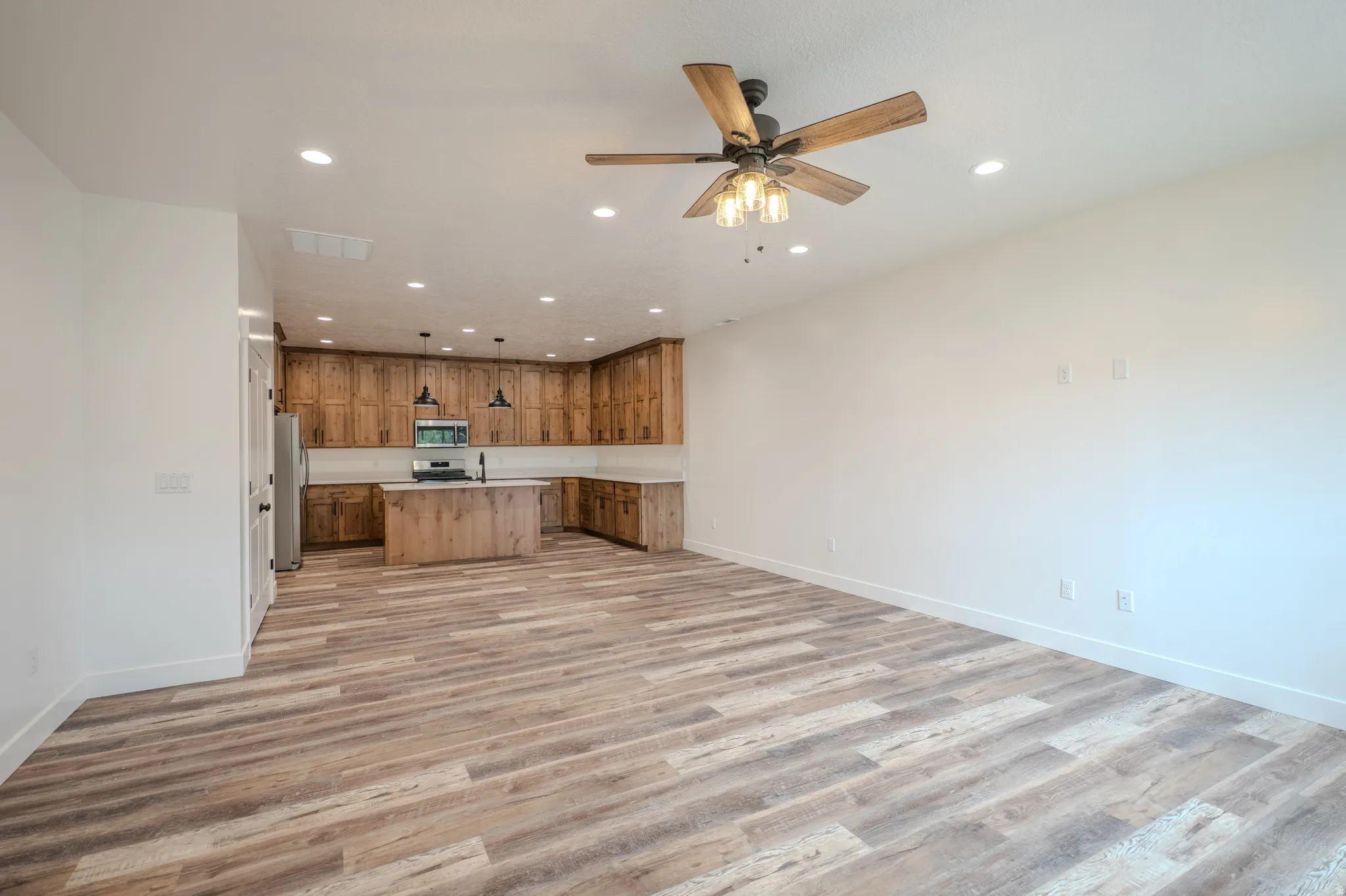 Open-concept living area featuring wood-finish flooring, recessed lighting, and a ceiling fan