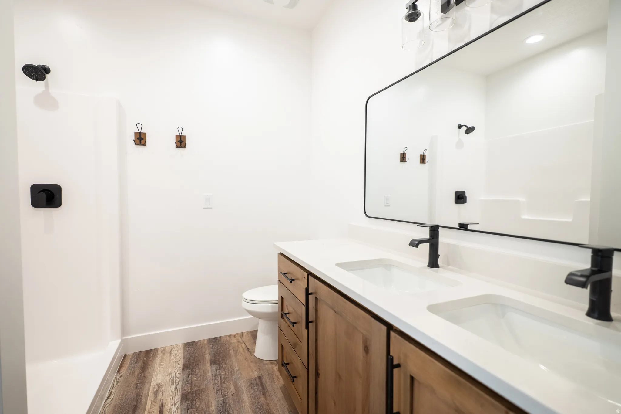 Bathroom featuring a dual vanity with light wood-finish cabinetry and matte black hardware