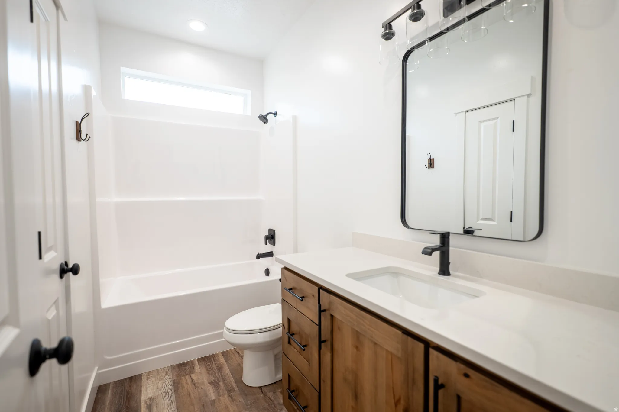 Bathroom featuring a single vanity with wood-finish cabinetry, a light-toned countertop, and an integrated rectangular sink