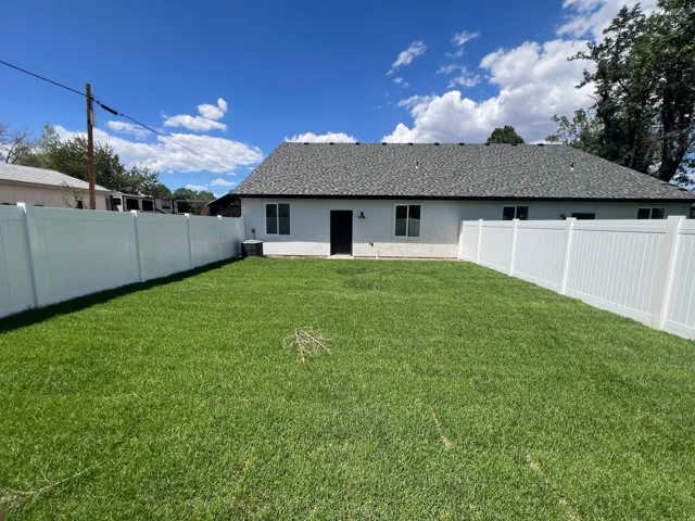 Expansive green lawn with complete white vinyl fencing