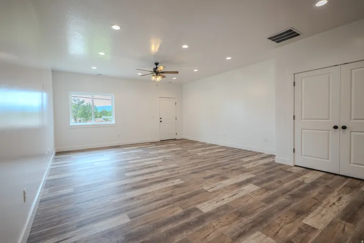 Spacious interior room featuring wood-finish flooring, recessed lighting, and a ceiling fan with integrated light fixture