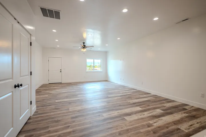 Spacious room featuring wood-finish flooring, recessed lighting, and a ceiling fan