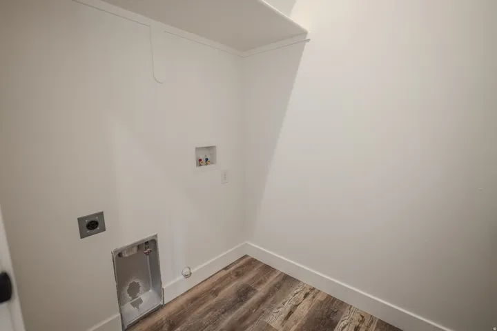 Dedicated utility space featuring wood-finish flooring, white walls, and a built-in shelf