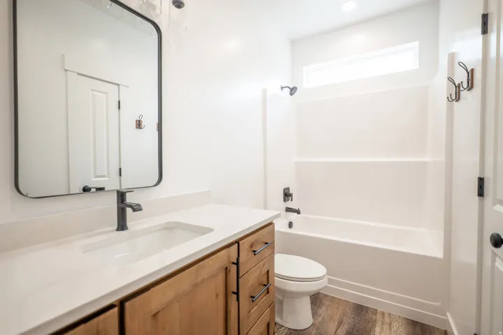 Bathroom featuring a light wood-finish vanity with a white countertop and integrated sink, matte black faucet, and a black-framed rectangular mirror
