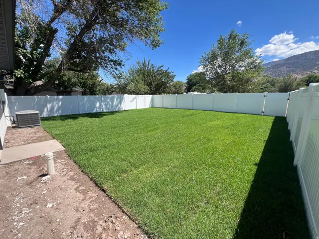 Expansive green lawn enclosed by a white vinyl privacy fence