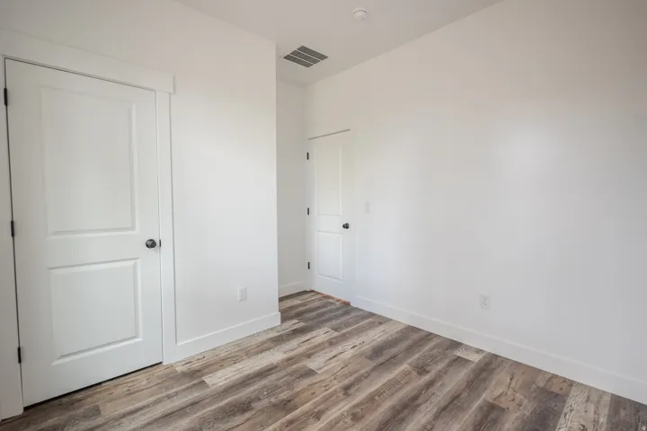 Interior room featuring wood-finish flooring, crisp white walls, and white trim