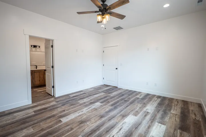 Spacious room featuring wood-finish flooring and a ceiling fan with integrated lighting