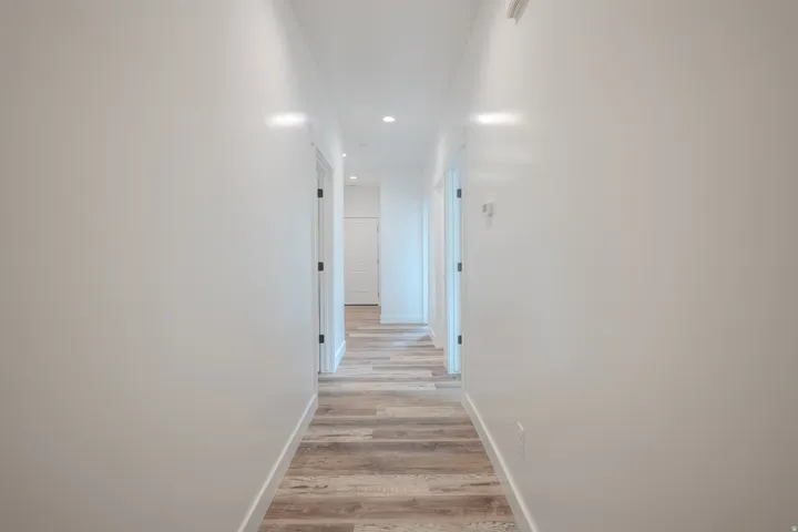 Hallway featuring wood-finish flooring, recessed lighting, white walls, and white trim