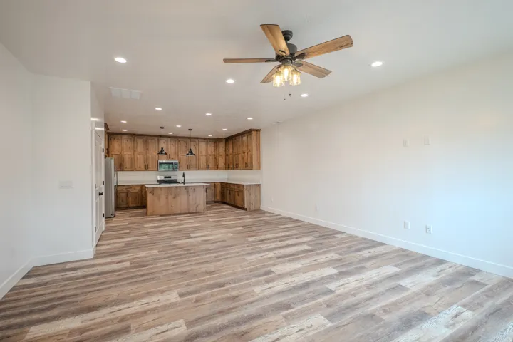 Open-concept living area featuring wood-finish flooring, recessed lighting, and a ceiling fan