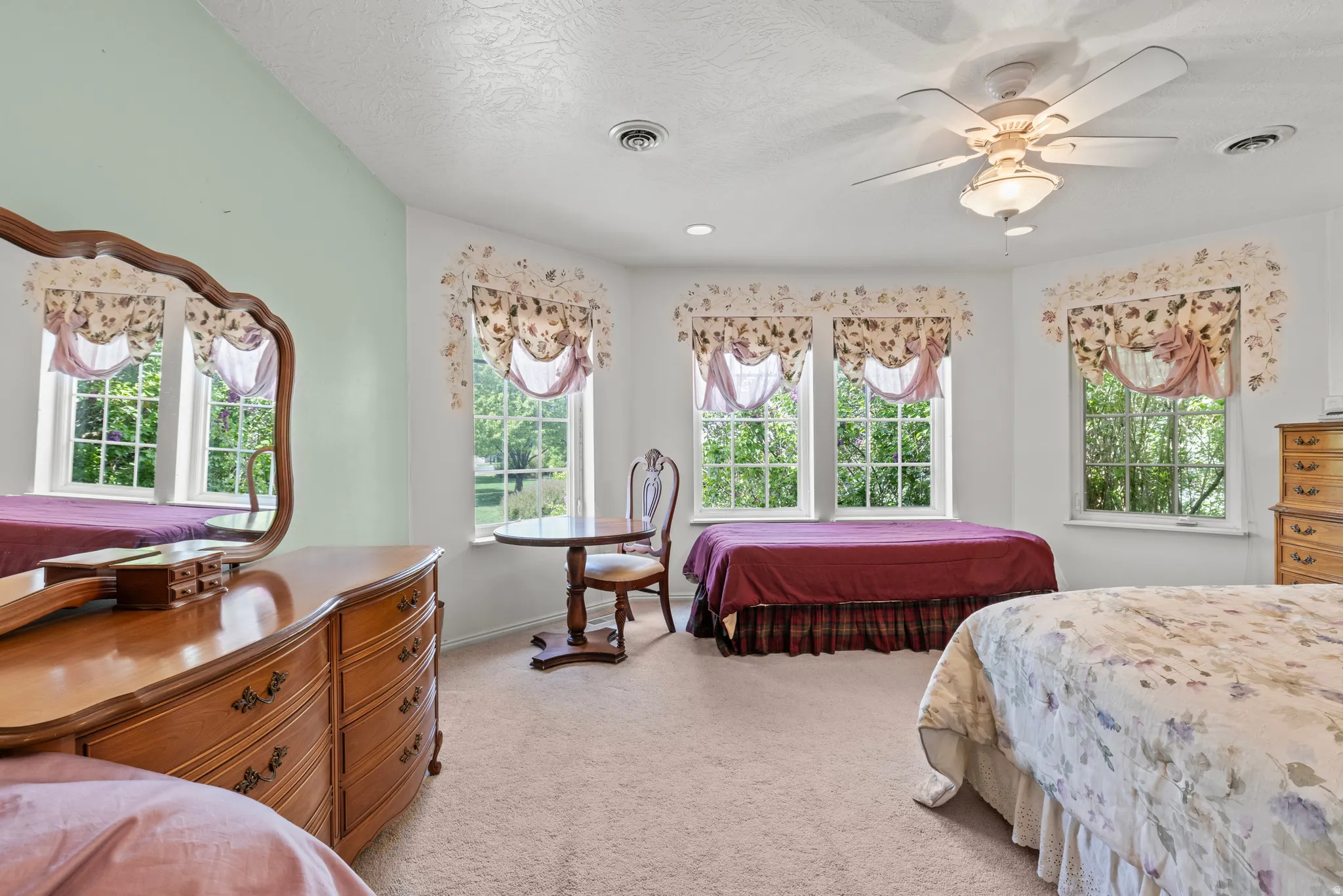 Room featuring a neutral carpet, multiple windows with natural light, a sloped ceiling, and a ceiling fan with integrated lighting
