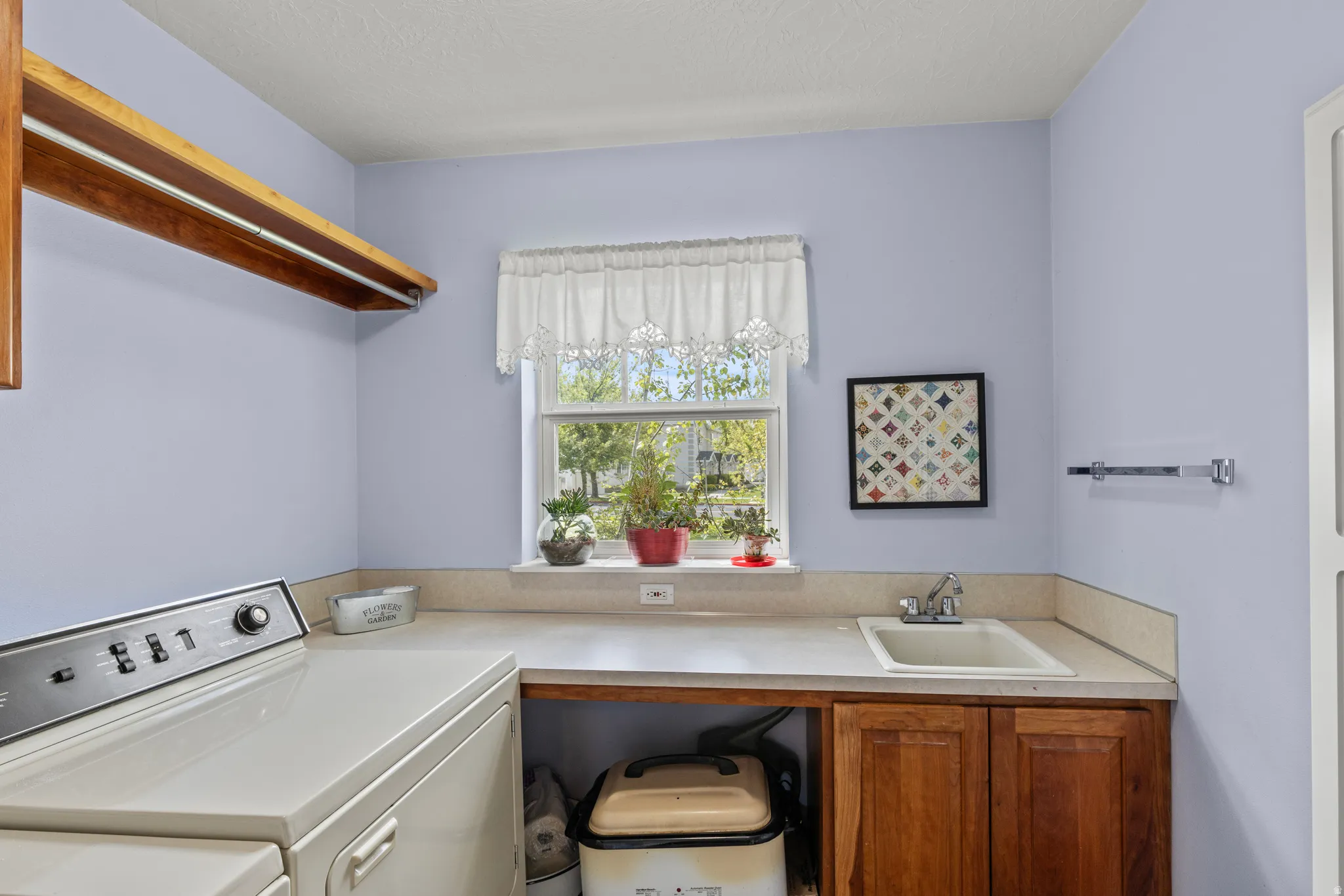 Dedicated laundry space featuring a utility sink, wood cabinetry, and a countertop