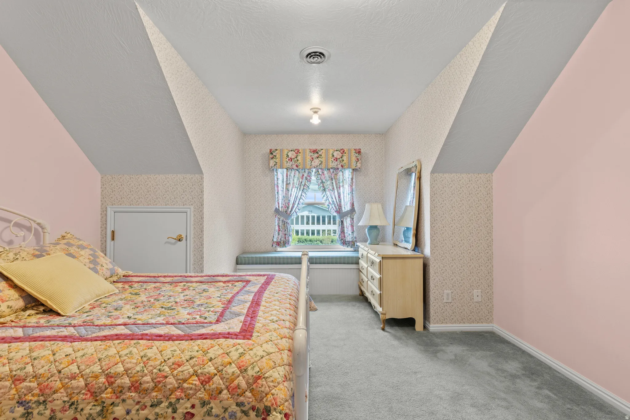 Room featuring a window seat with a cushioned surface, sloped ceilings, and gray carpeting
