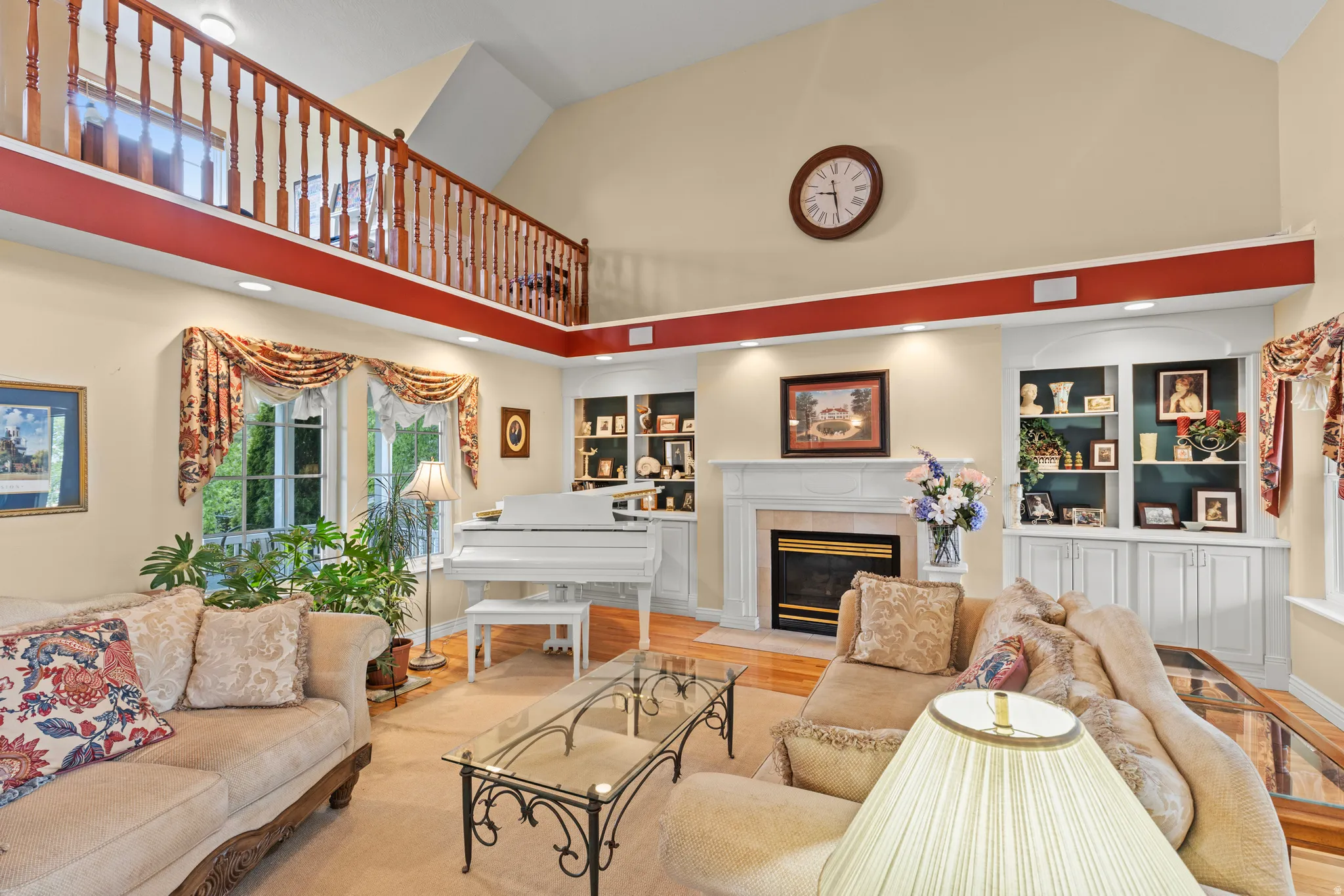 Two-story living area featuring a vaulted ceiling, a second-story wood-baluster railing, and a fireplace with a white mantel