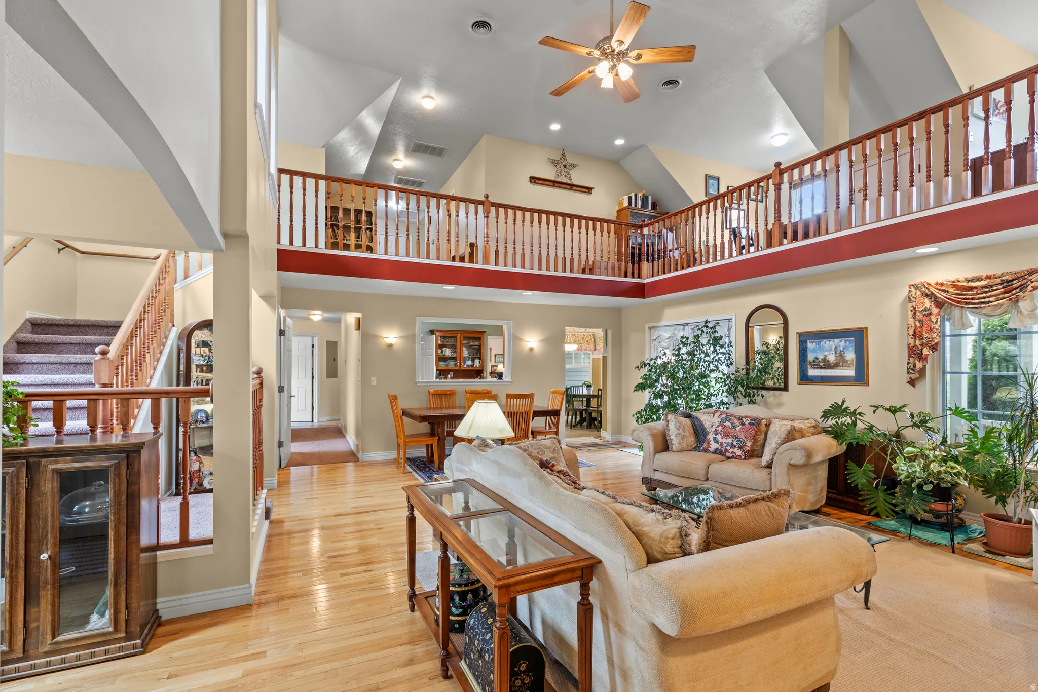 Spacious living area featuring high vaulted ceilings, natural wood-finish flooring, and a second-story open balcony overlooking the space