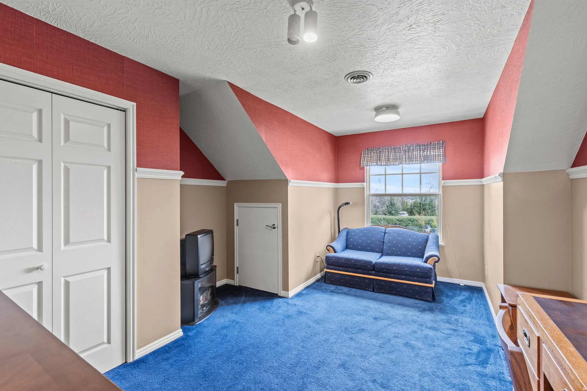 Carpeted room with a multi-pane window and a textured ceiling