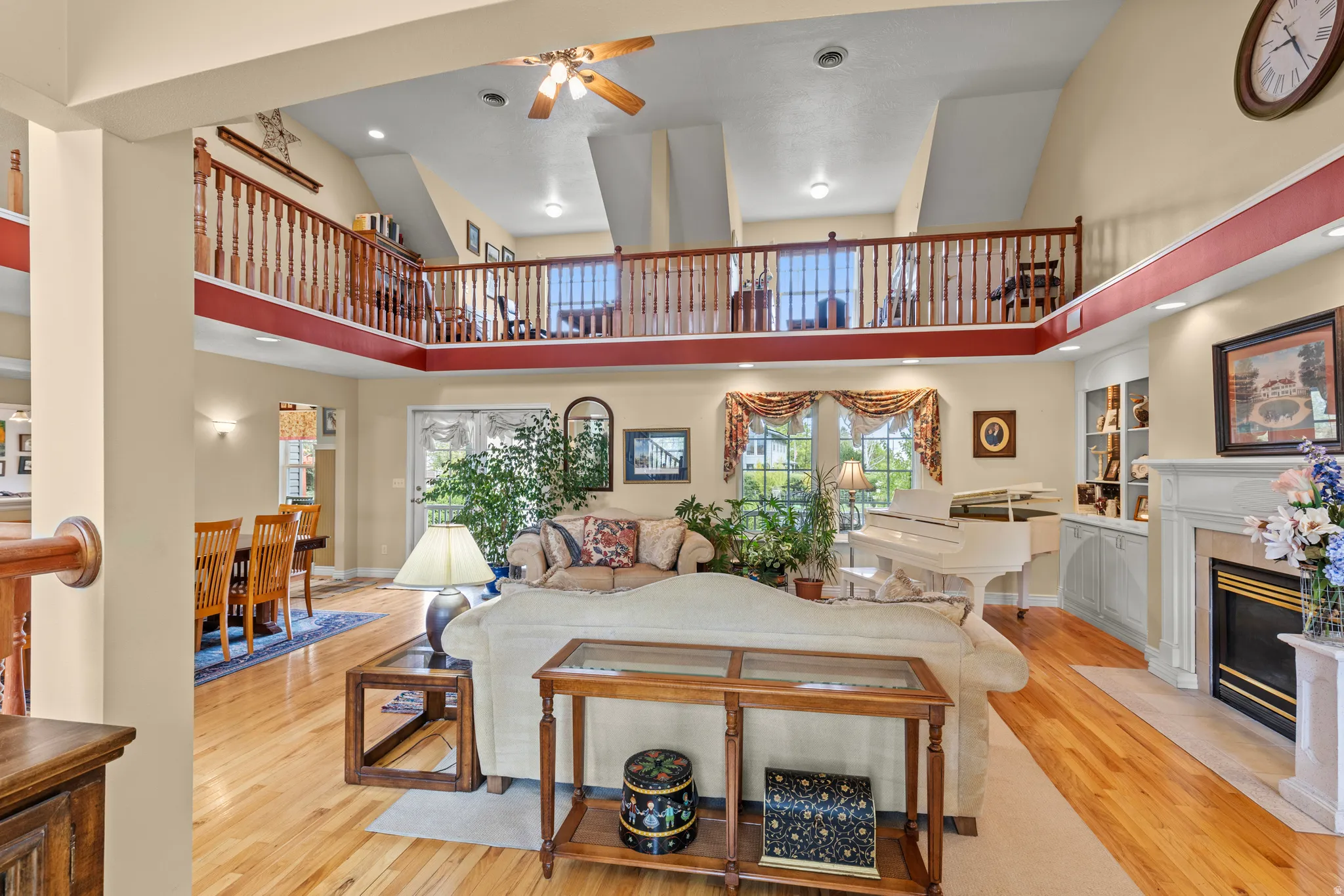 Two-story living area featuring wood-finish flooring and a stone-surround fireplace with a white mantel
