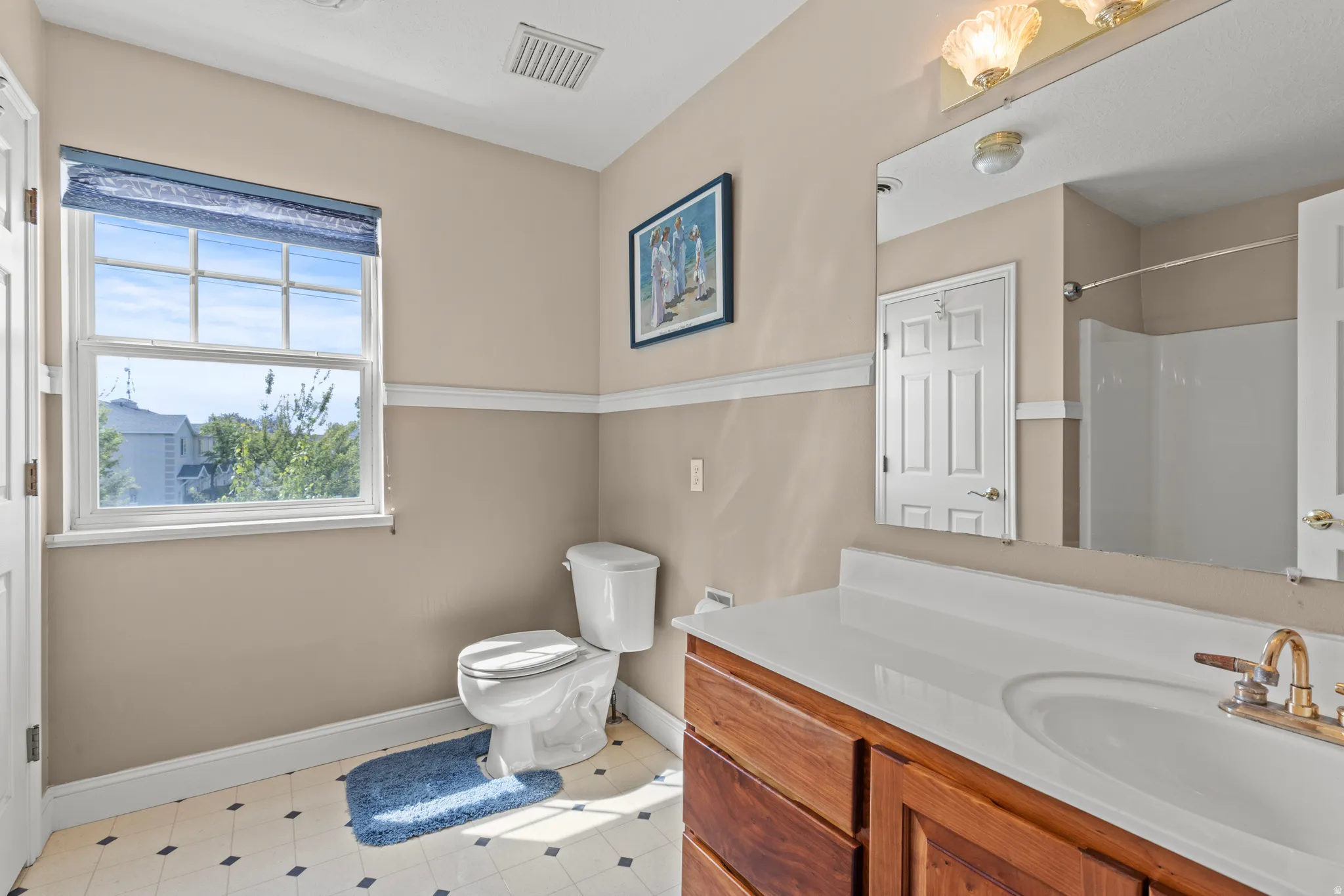 Full bathroom featuring a single vanity with wood cabinetry, a white countertop, and an integrated sink with brass-finish fixtures