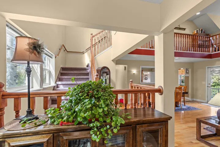 Interior space featuring wood-finish flooring, a wood baluster railing system, and a carpeted staircase