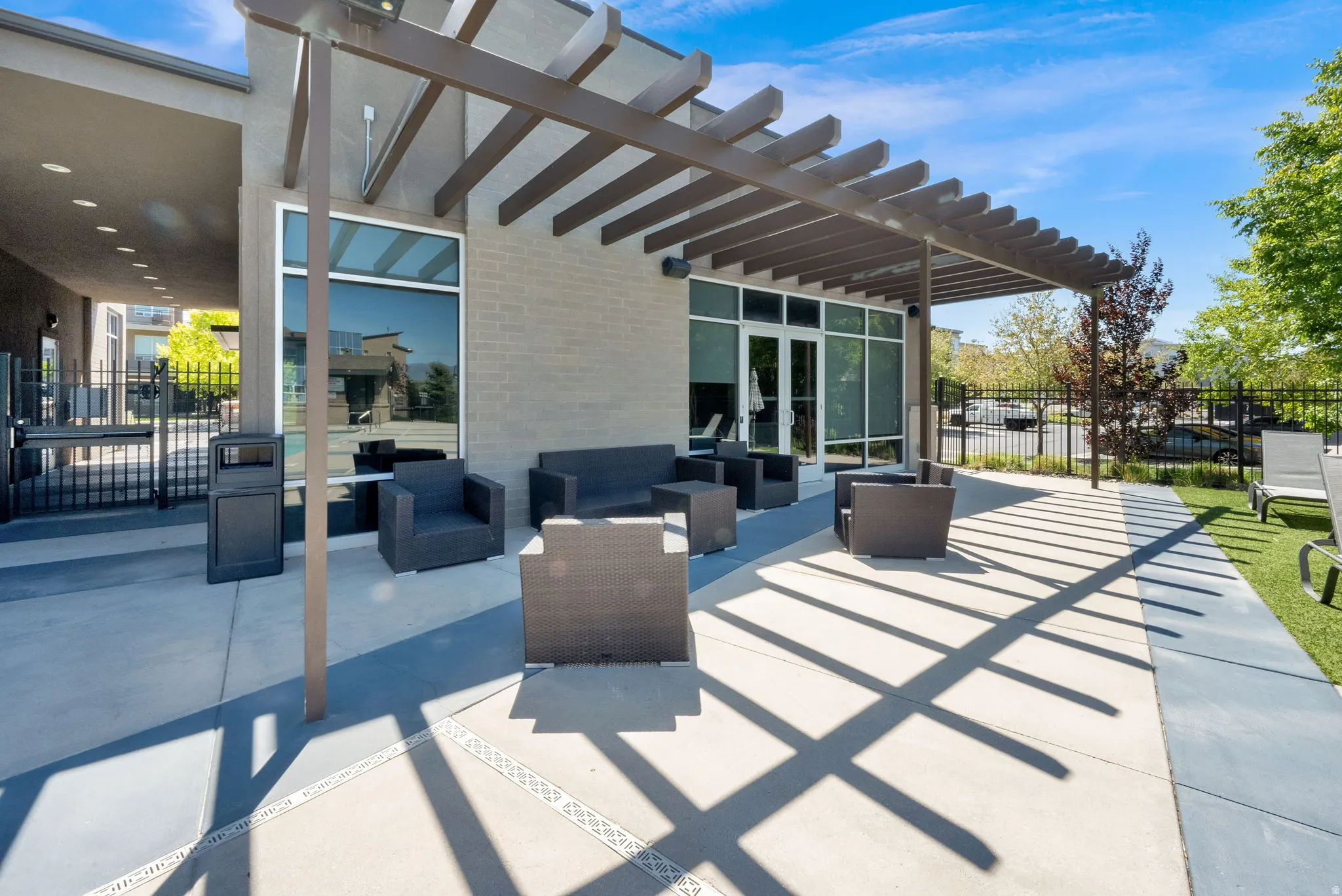 Outdoor patio with a slatted pergola, featuring concrete paving and an artificial turf area