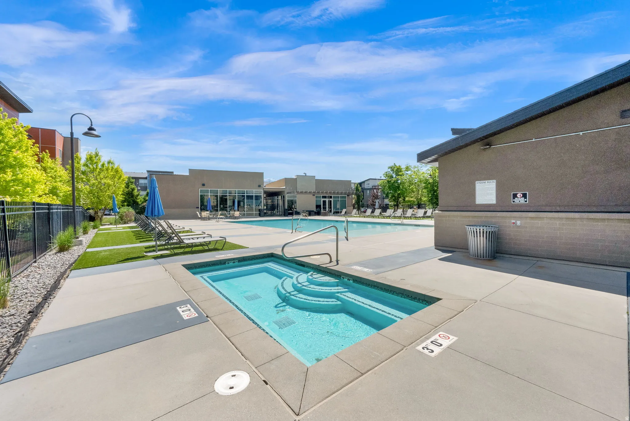 Pool area featuring a hot tub with integrated steps, a large swimming pool, and a surrounding concrete deck