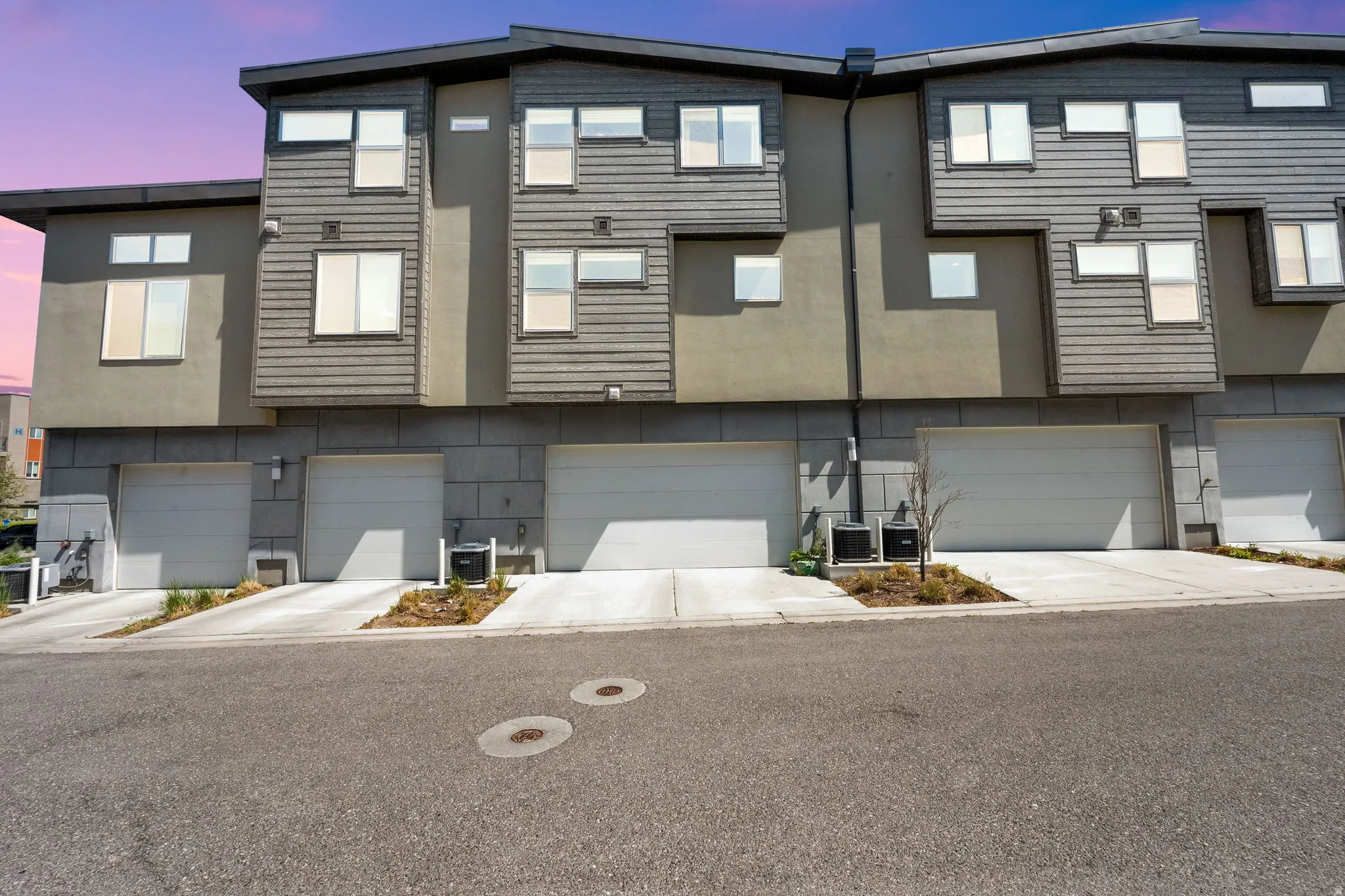 Modern multi-level townhome featuring a neutral stucco and horizontal siding facade