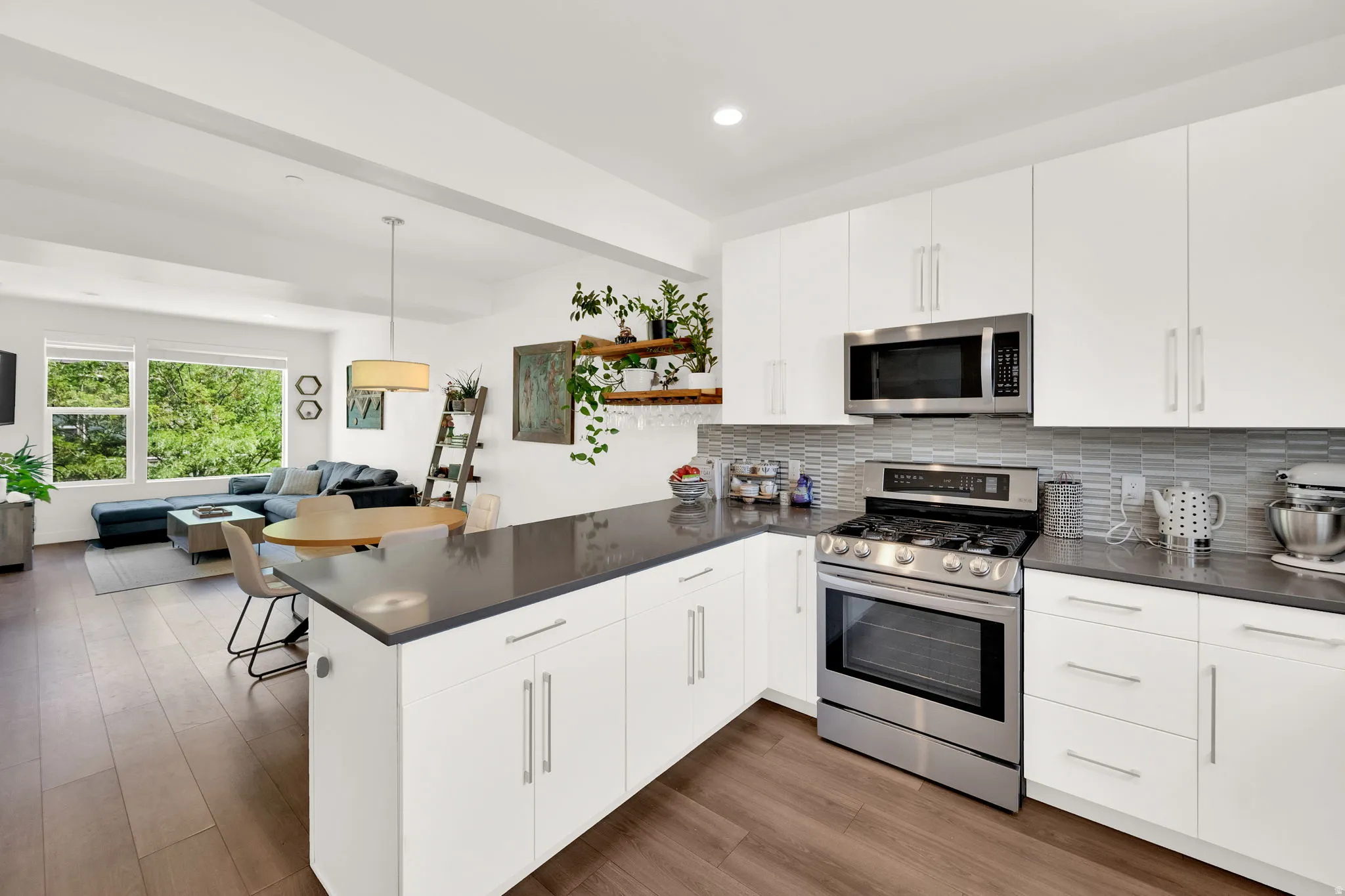 Modern kitchen featuring white cabinetry, stainless steel appliances, dark countertops, and a tiled backsplash