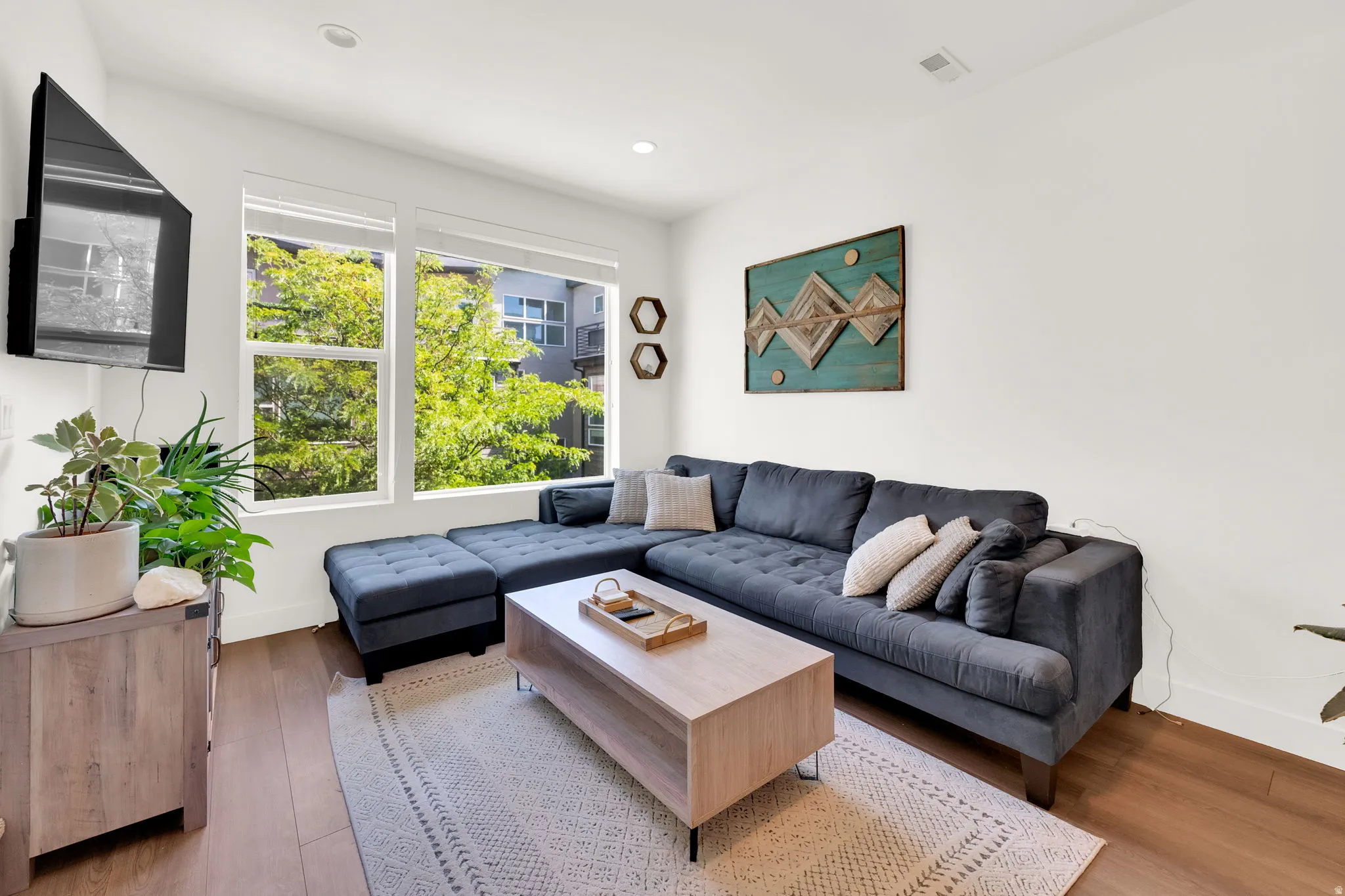 Living area featuring expansive windows, wood-finish flooring, recessed lighting, and a neutral color palette