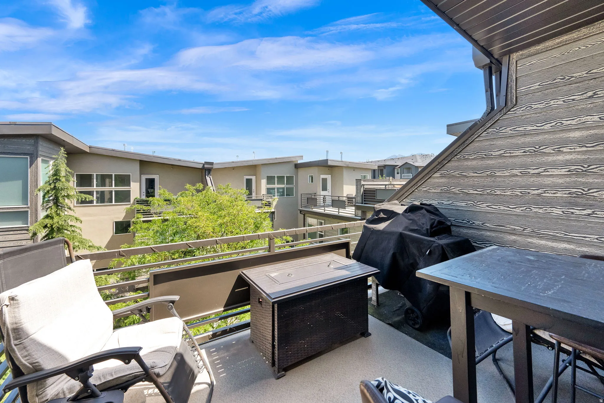 Expansive outdoor deck featuring a gray concrete surface, dark gray wood-look accent wall, and metal railings