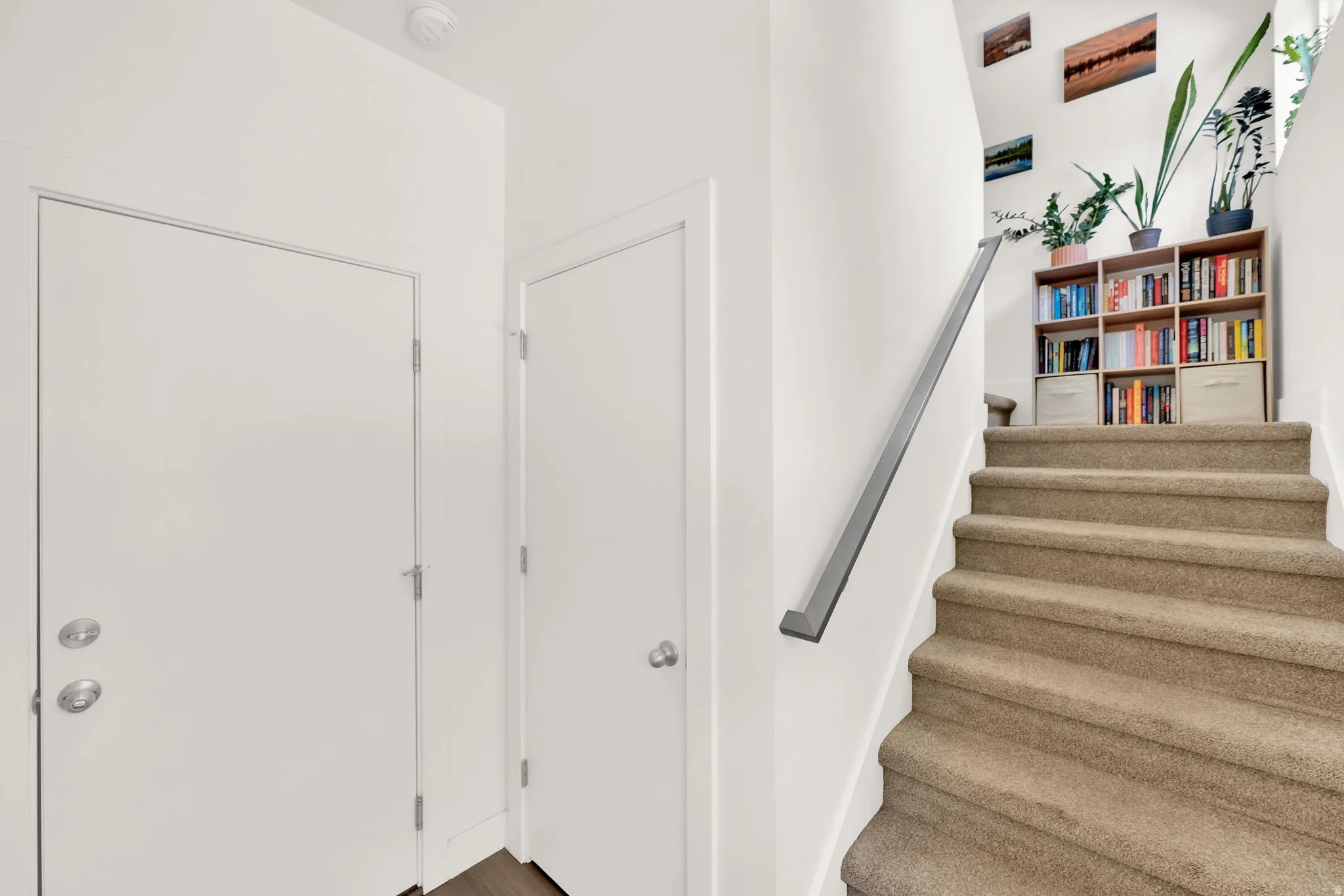 Carpeted staircase featuring a contemporary metal handrail and light-toned walls