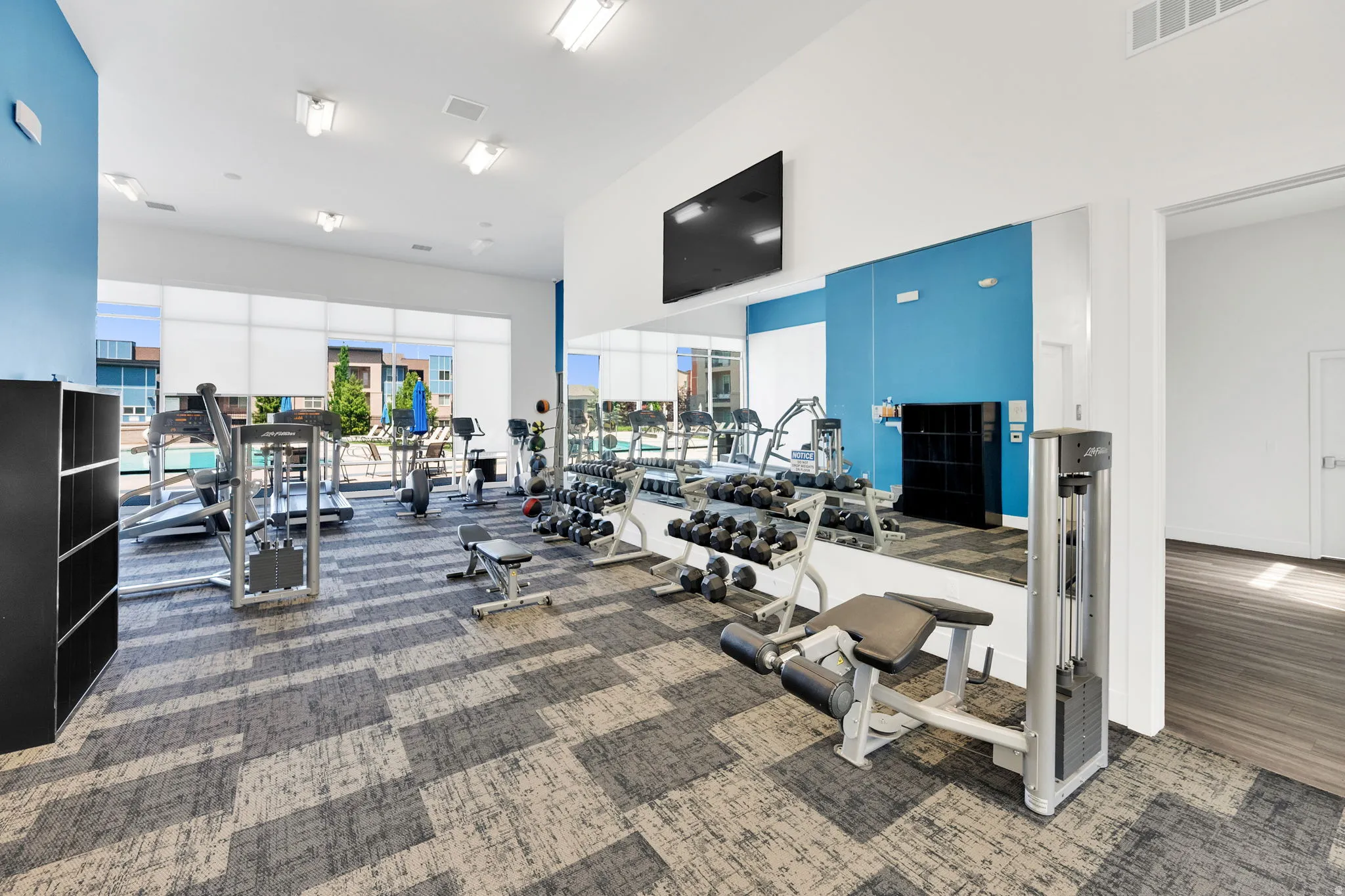 Fitness center with patterned carpet, large windows, recessed lighting, and mirrored wall
