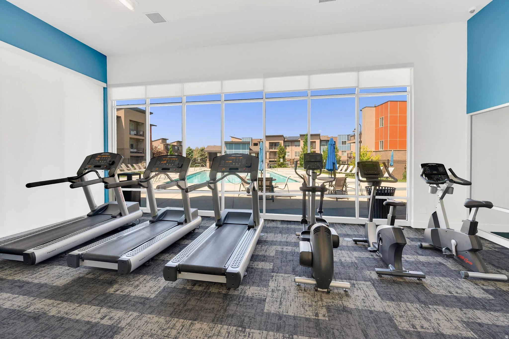 Fitness center with a large window overlooking the outdoor swimming pool