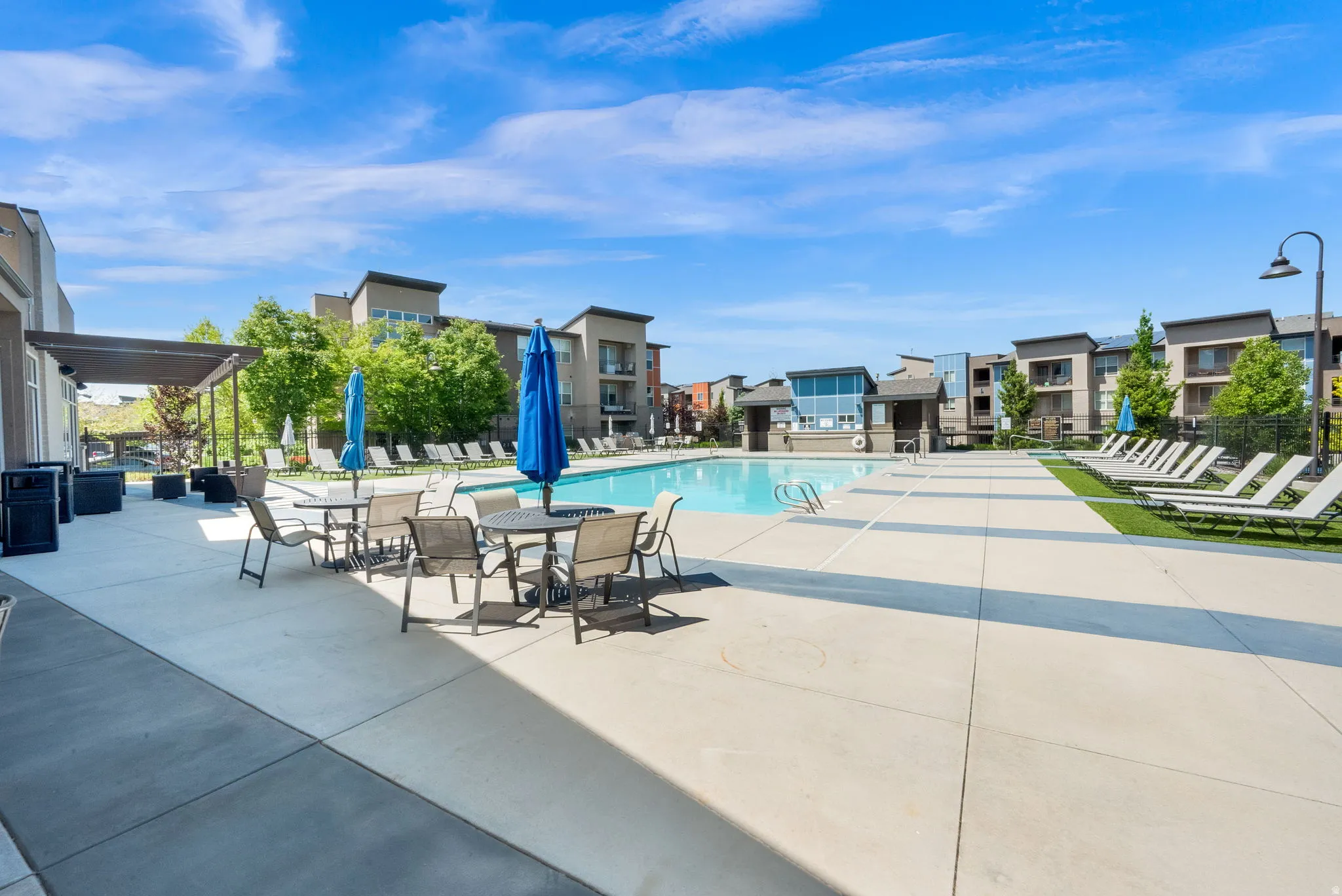 Outdoor swimming pool with surrounding concrete decking, artificial turf, and multiple lounge chairs