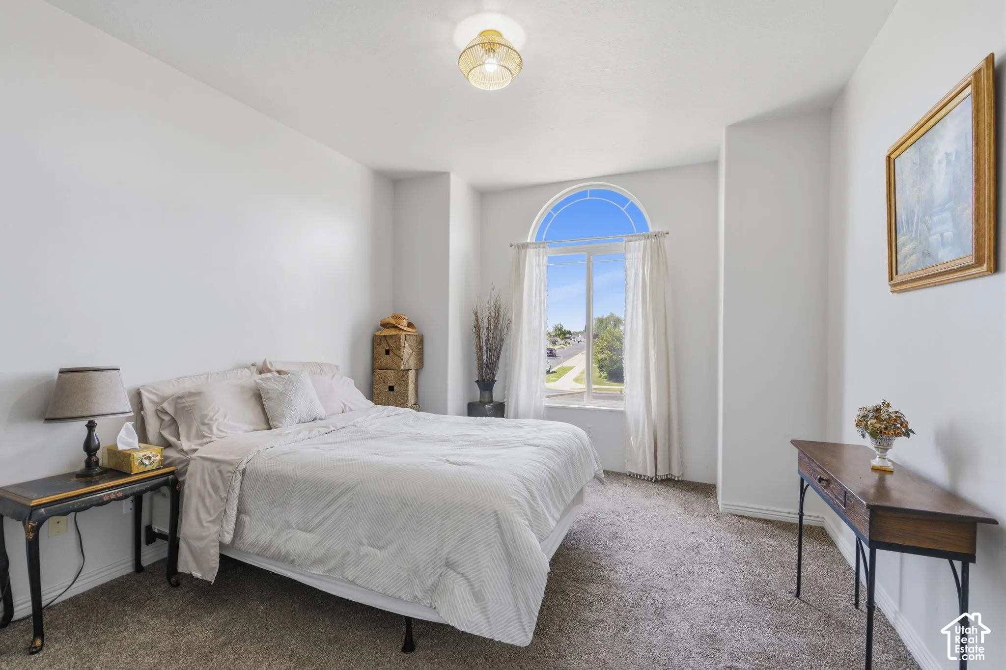 Arch-top window with white trim, light-colored walls, carpeted flooring, and a ceiling-mounted light fixture