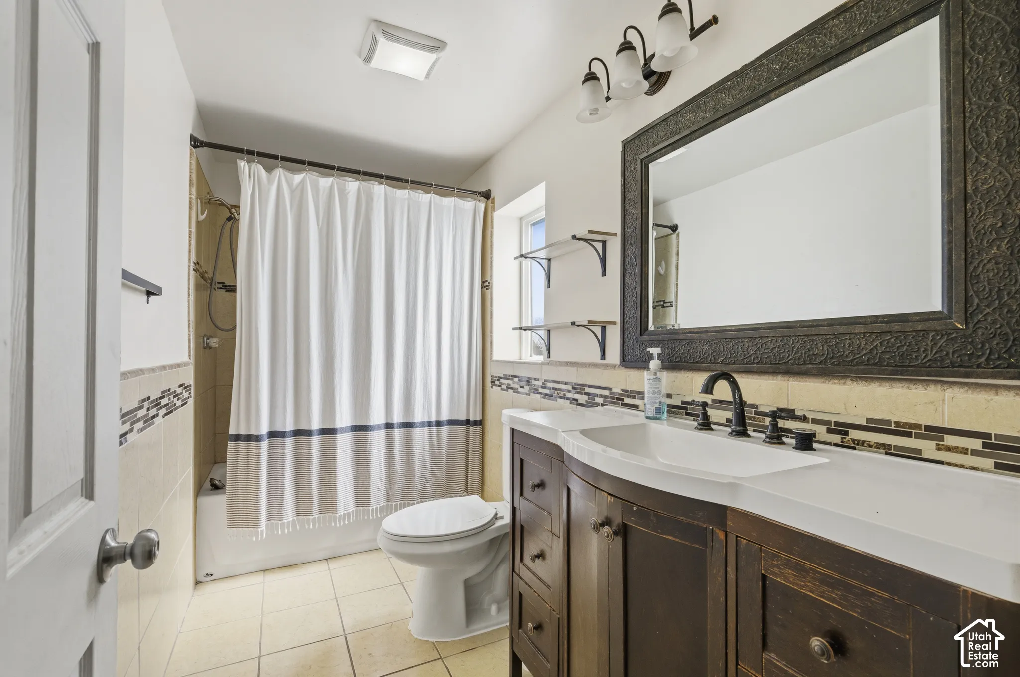 Bathroom with a curved vanity, integrated sink, and an ornate framed mirror