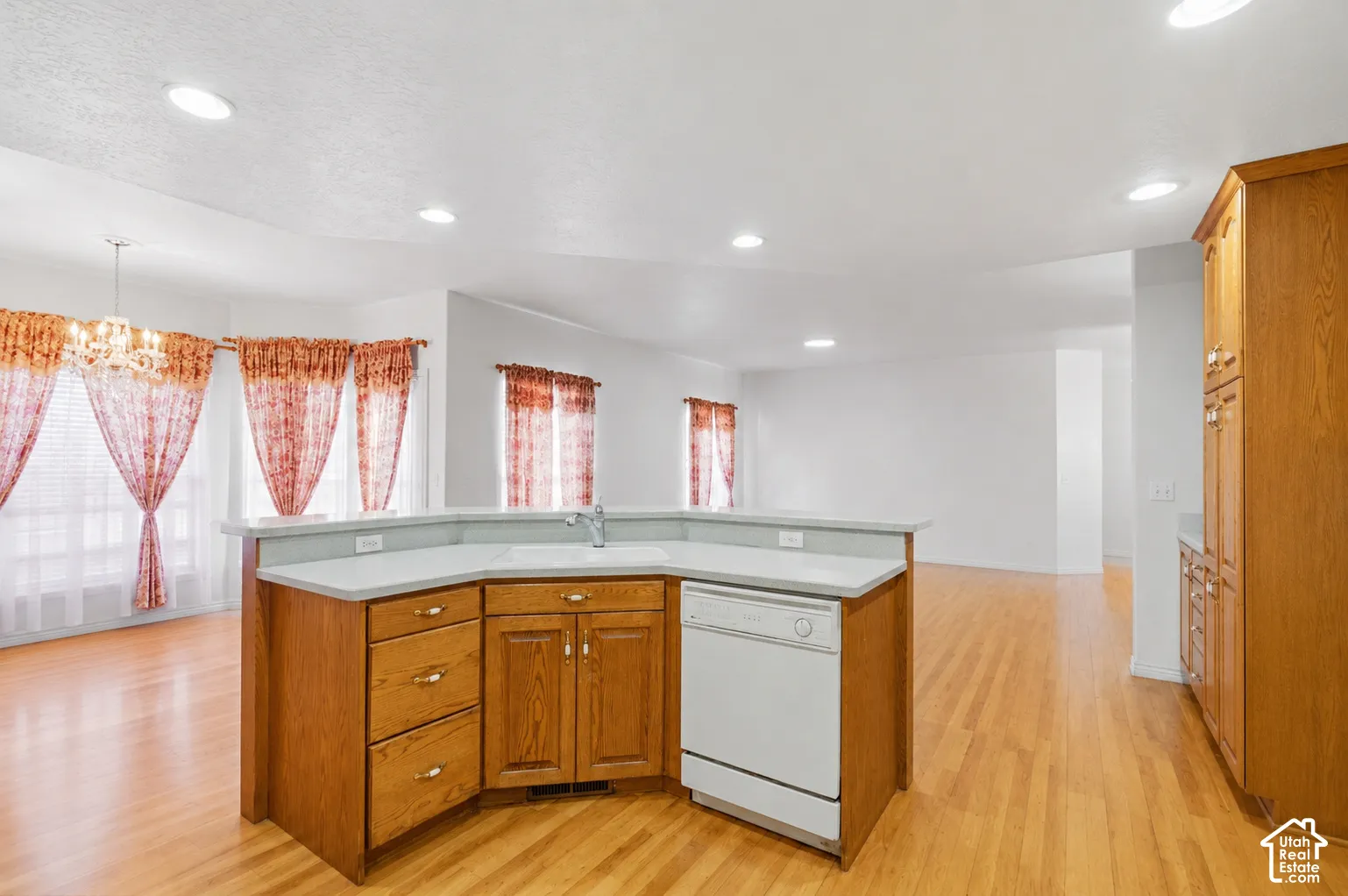 Wood-finish flooring throughout, recessed lighting, and a kitchen island with integrated sink