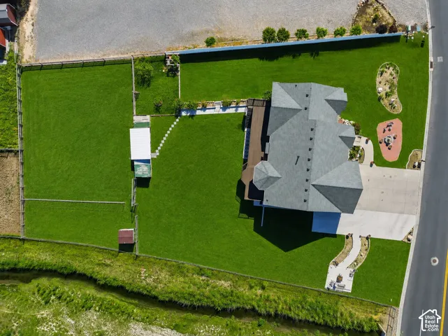 Expansive lot featuring a large green lawn, a multi-gabled roofline, concrete driveway, and a backyard deck