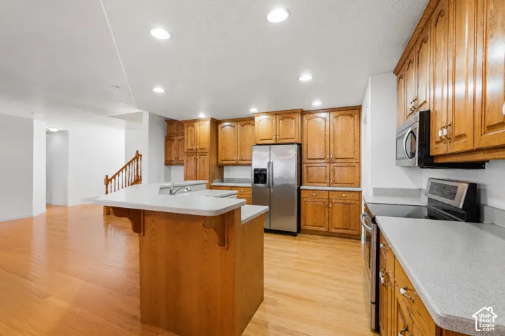 Kitchen featuring wood-finish cabinetry, light-toned countertops, and stainless steel appliances