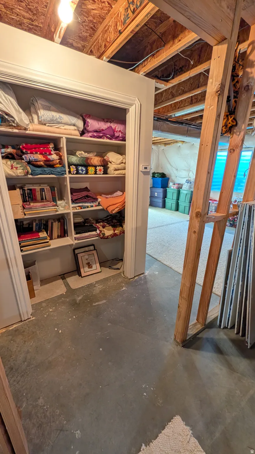 Built-in shelving unit with multiple storage compartments, exposed ceiling joists, and concrete flooring