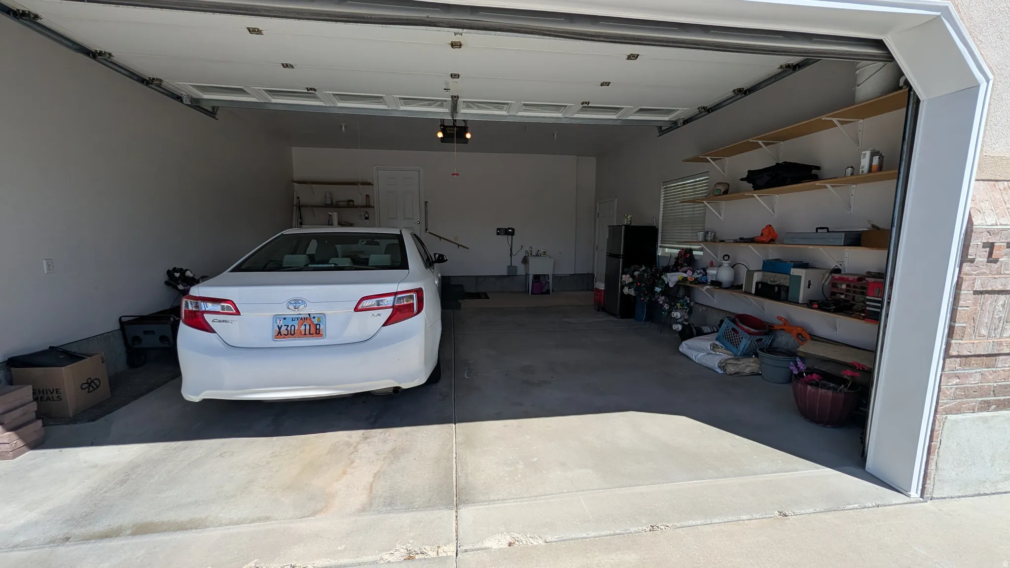 Spacious garage featuring a concrete floor, overhead lighting, and built-in shelving for organized storage