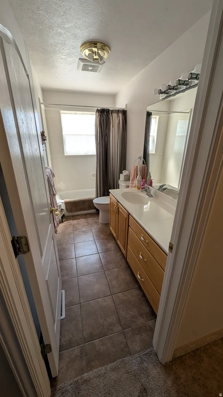 Bathroom featuring a light wood-finish vanity with a white countertop and integrated sink, a rectangular wall mirror, and a multi-bulb vanity light fixture