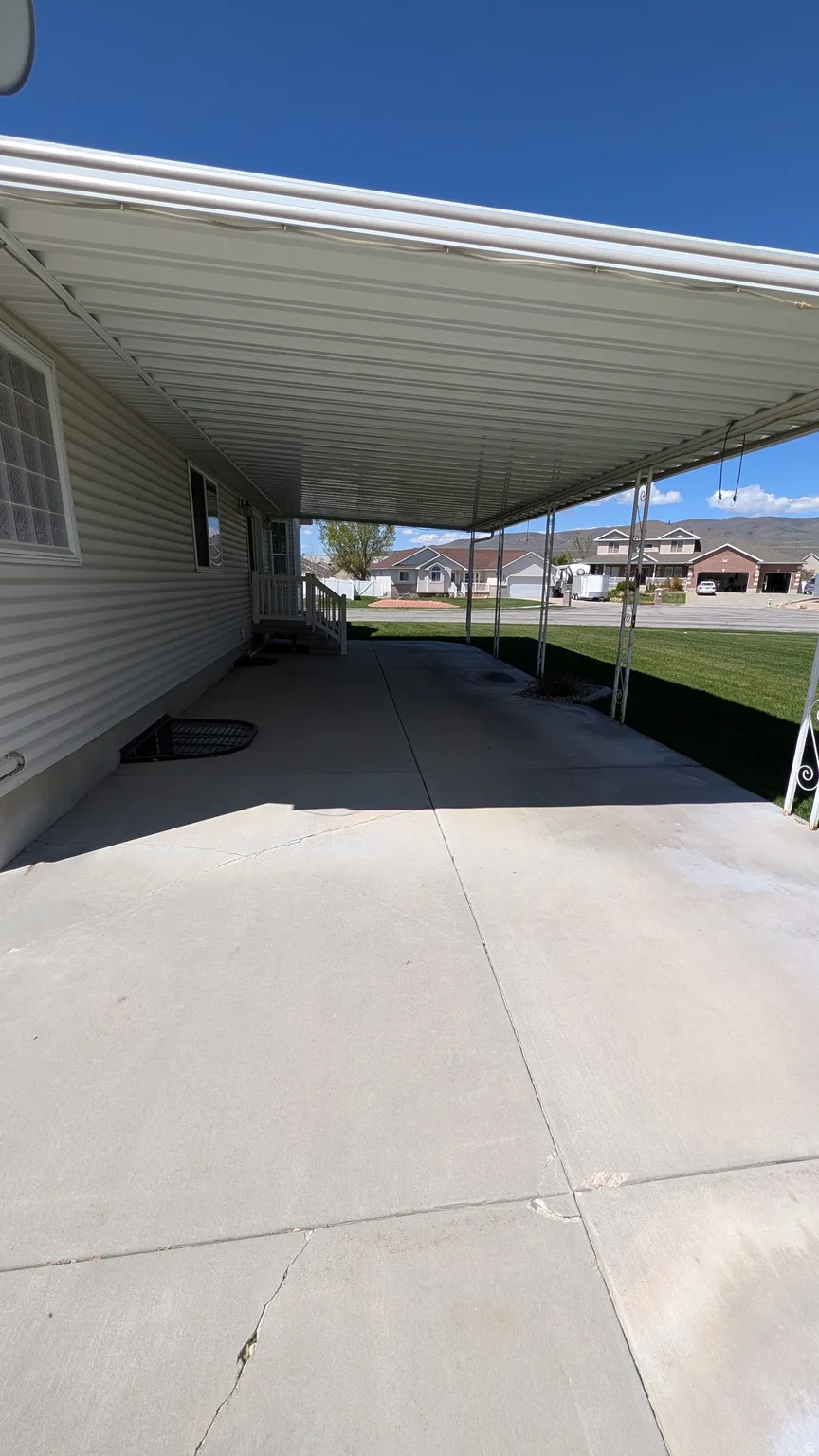 Expansive concrete driveway featuring a metal carport structure