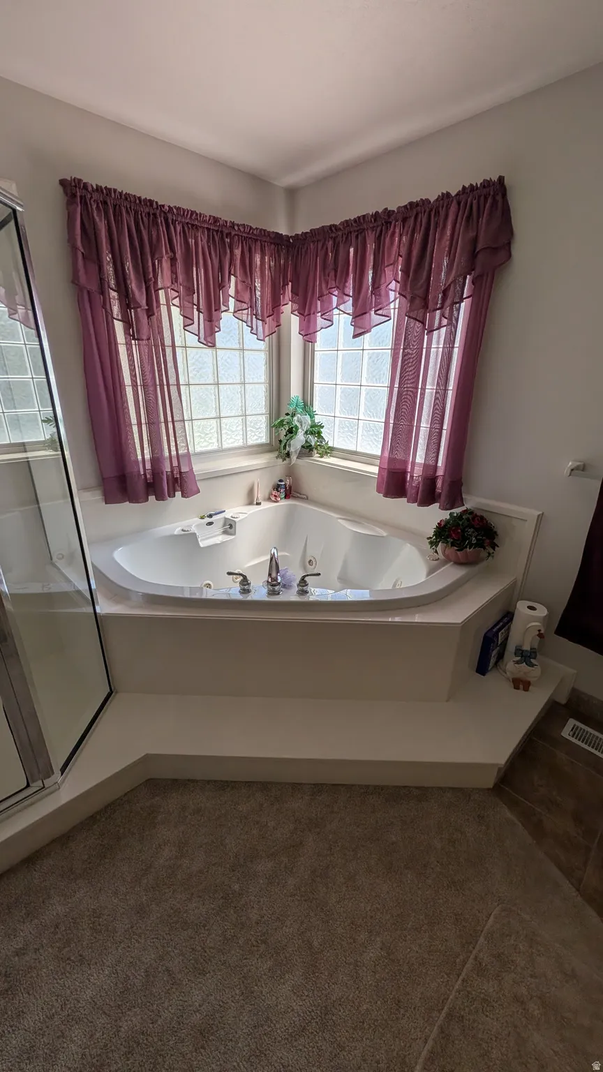 Corner soaking tub with polished chrome fixtures, surrounded by glass block windows