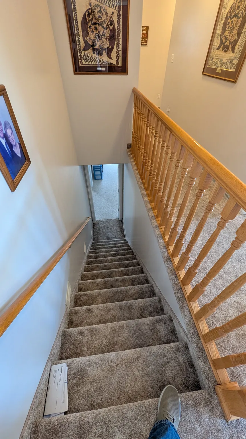 Carpeted staircase with light-toned wooden handrails and balusters