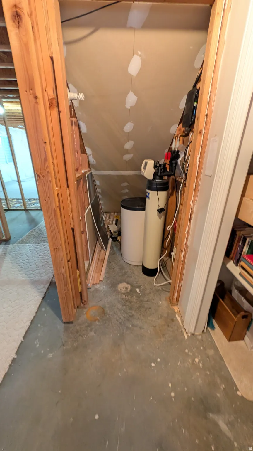 Utility area featuring a water softener system, water heater, and concrete flooring