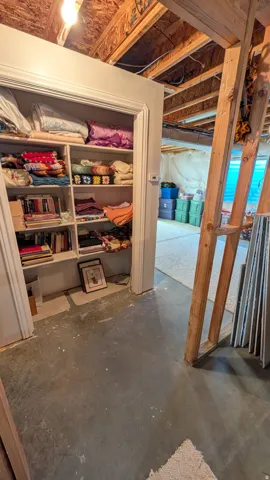 Built-in shelving unit with multiple storage compartments, exposed ceiling joists, and concrete flooring