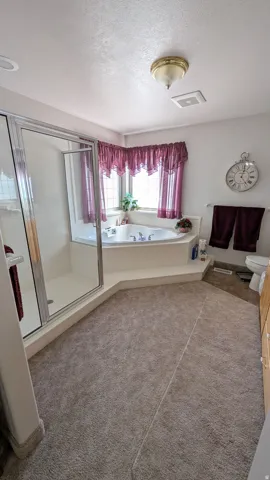 Bathroom featuring a jetted corner tub, enclosed glass shower, recessed lighting, and a vanity with wood-finish cabinetry